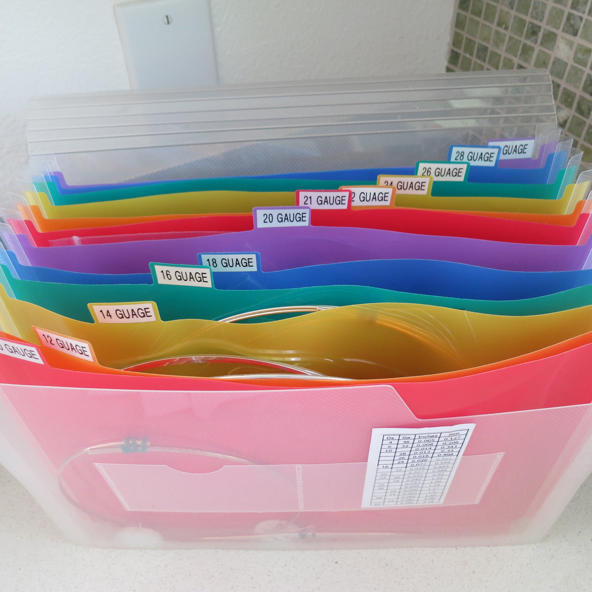 Silver wire sorted by gauge in a colorful file folder