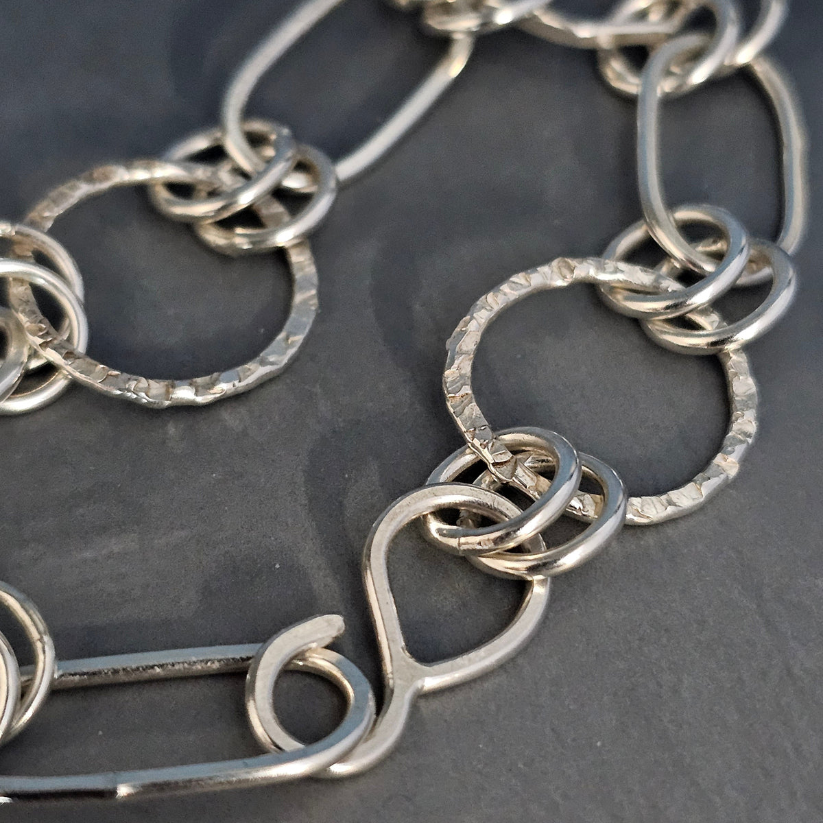 Close-up of the silver bracelet's hammered links and hook clasp