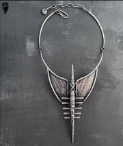 Ornate silver necklace on a textured gray background